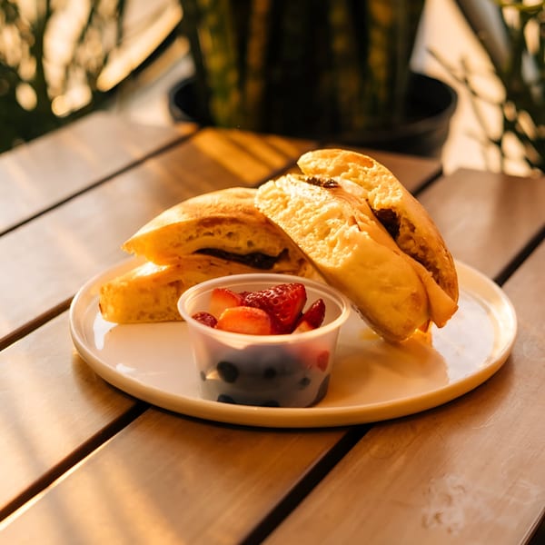 Golden-brown pastries with a side of fresh strawberries and blueberries on a white plate.