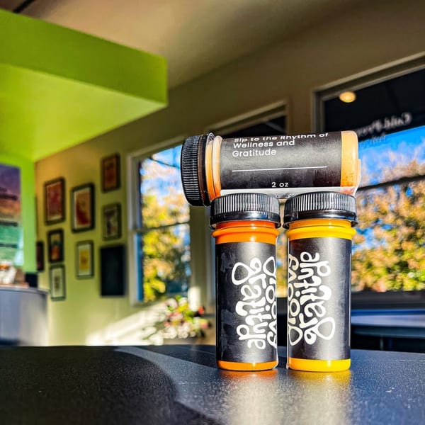 Three Groovy Gratitude wellness shots, two upright and one on its side, on a counter.